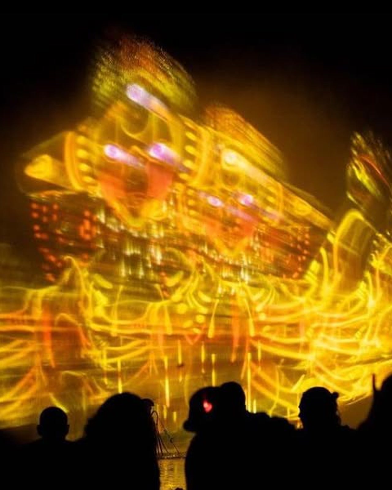 A visitor standing in front of a floating holographic figure of light in the dark at Boom Festival