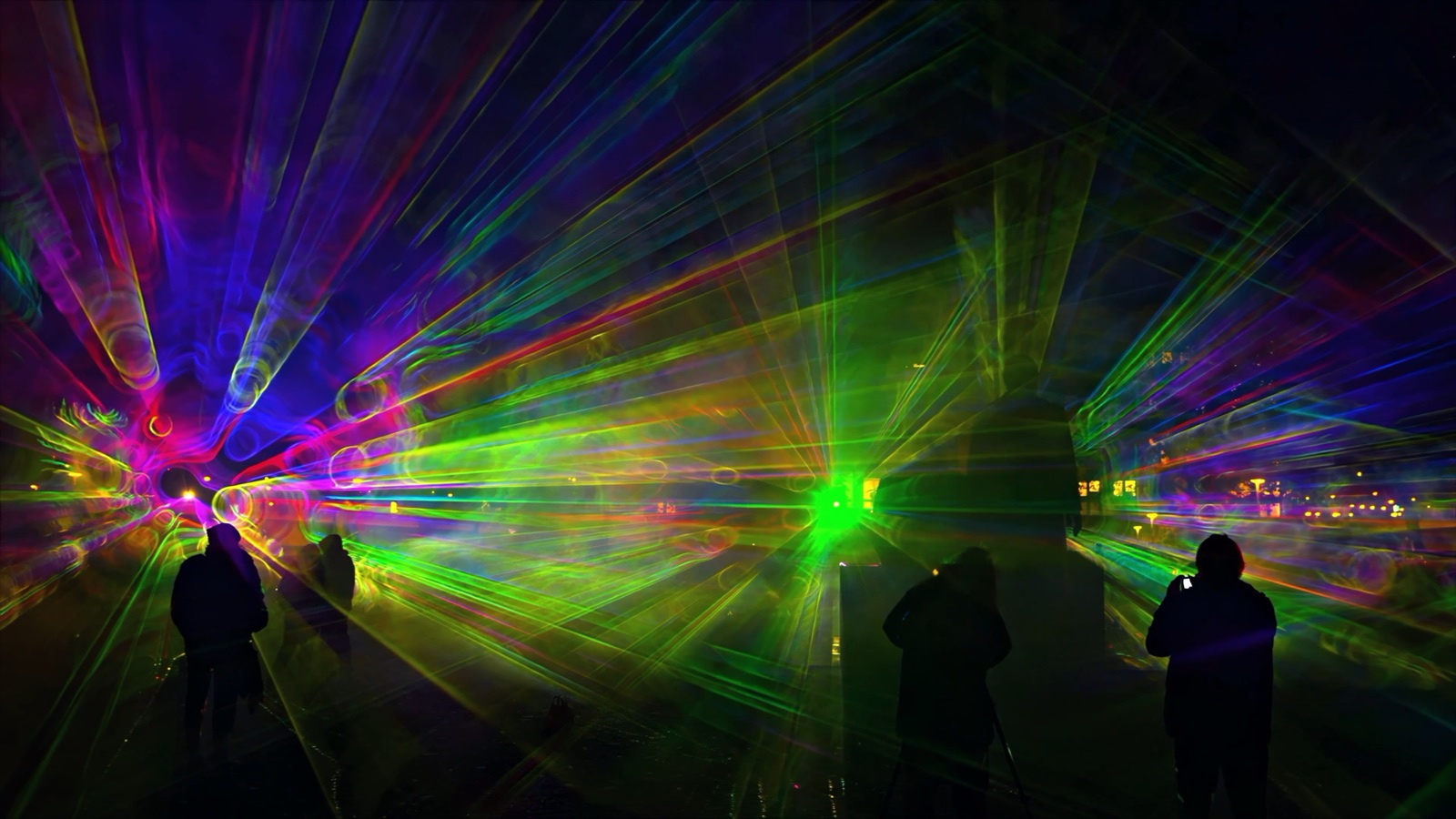 Visitors standing inside ÆTHER, a walk-in installation of green, magenta and blue light beams in fog at the Marx-Engels-Forum in Berlin