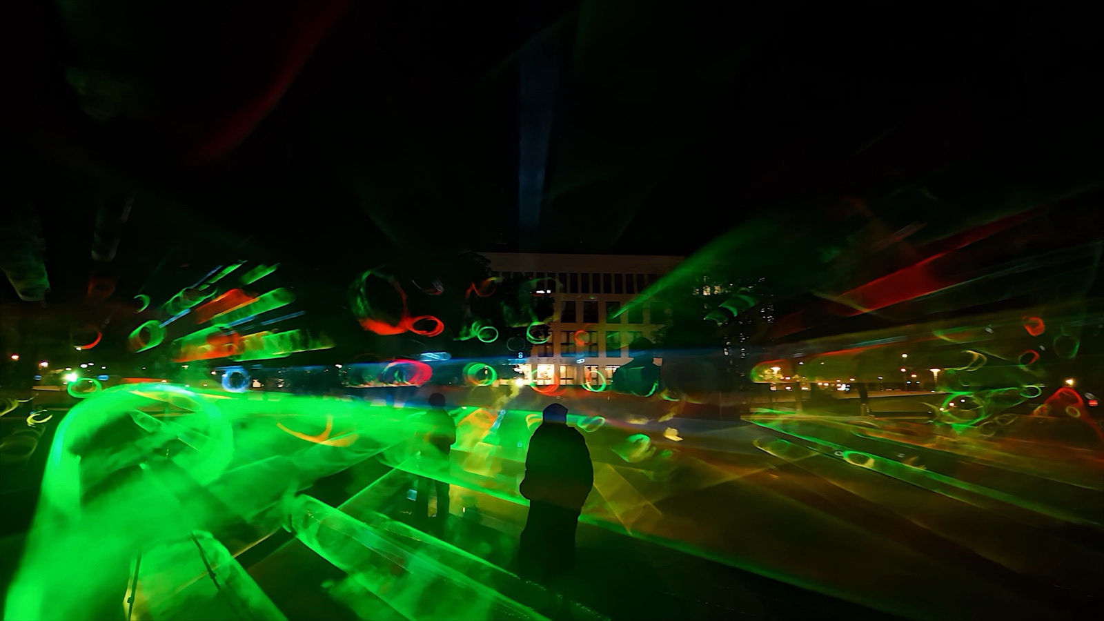 Visitors standing inside ÆTHER, a walk-in installation of green, magenta and blue light beams in fog at the Marx-Engels-Forum in Berlin