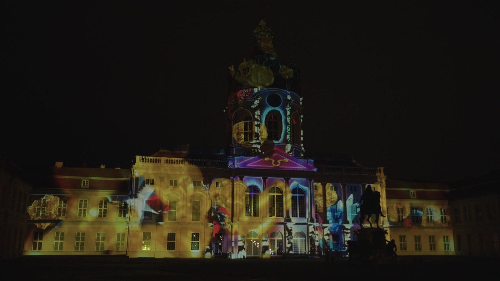 The baroque façade of Charlottenburg Palace in Berlin covered in a colourful 3D projection mapping of glowing data patterns
