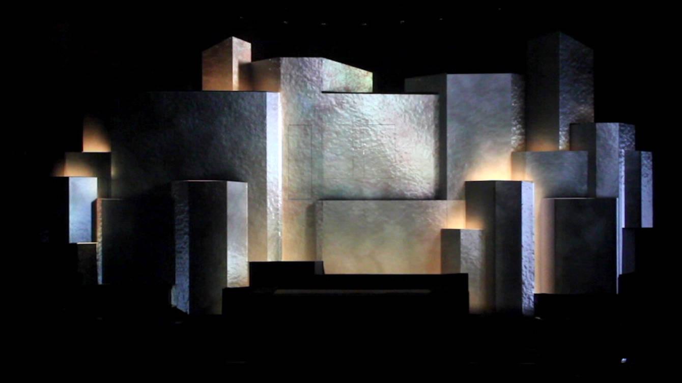 A stage of stacked projection-mapped volumes lit in pale grey and warm amber during the Hannover Messe opening ceremony
