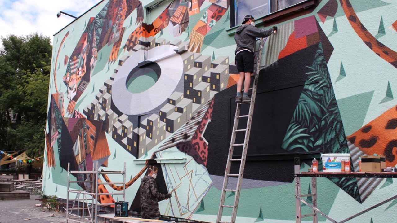 A colourful mural by the artist duo Low Bros on a wall at Urban Spree Berlin, seen in daylight while it was still being painted