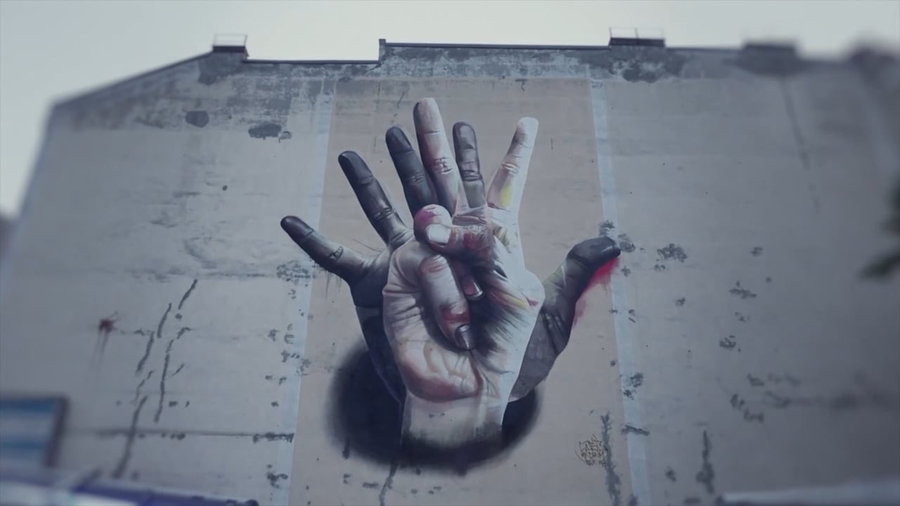 A large mural of two hands painted on a building wall