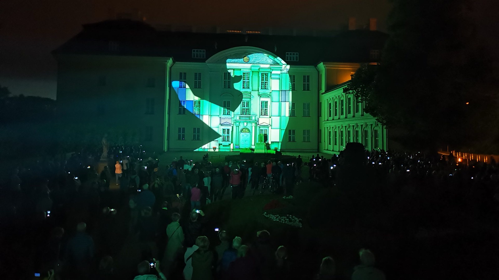 The silhouette of the Berlin bear projected in green and white across the centre of Schloss Köpenick, the audience holding up phones in the dark garden