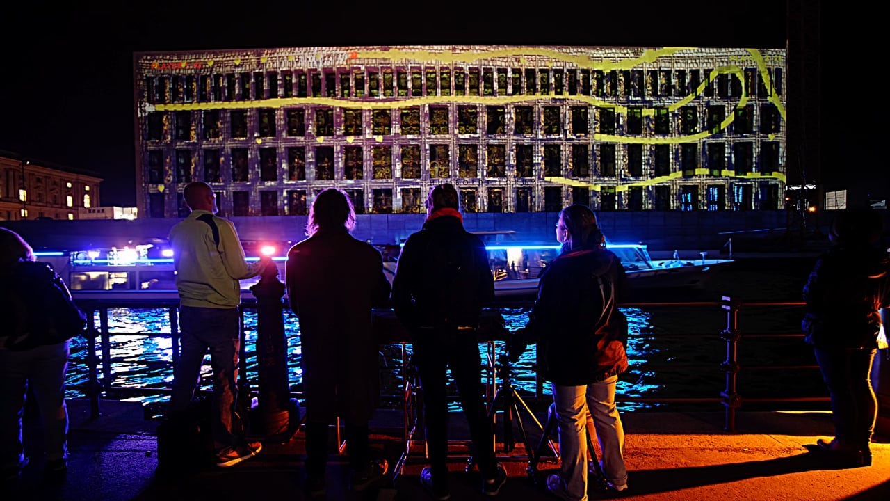 Spectators at the railing on the far bank of the Spree watching a multiplayer Snake game projected onto the Humboldt Forum in Berlin at night, Berlin leuchtet 2018