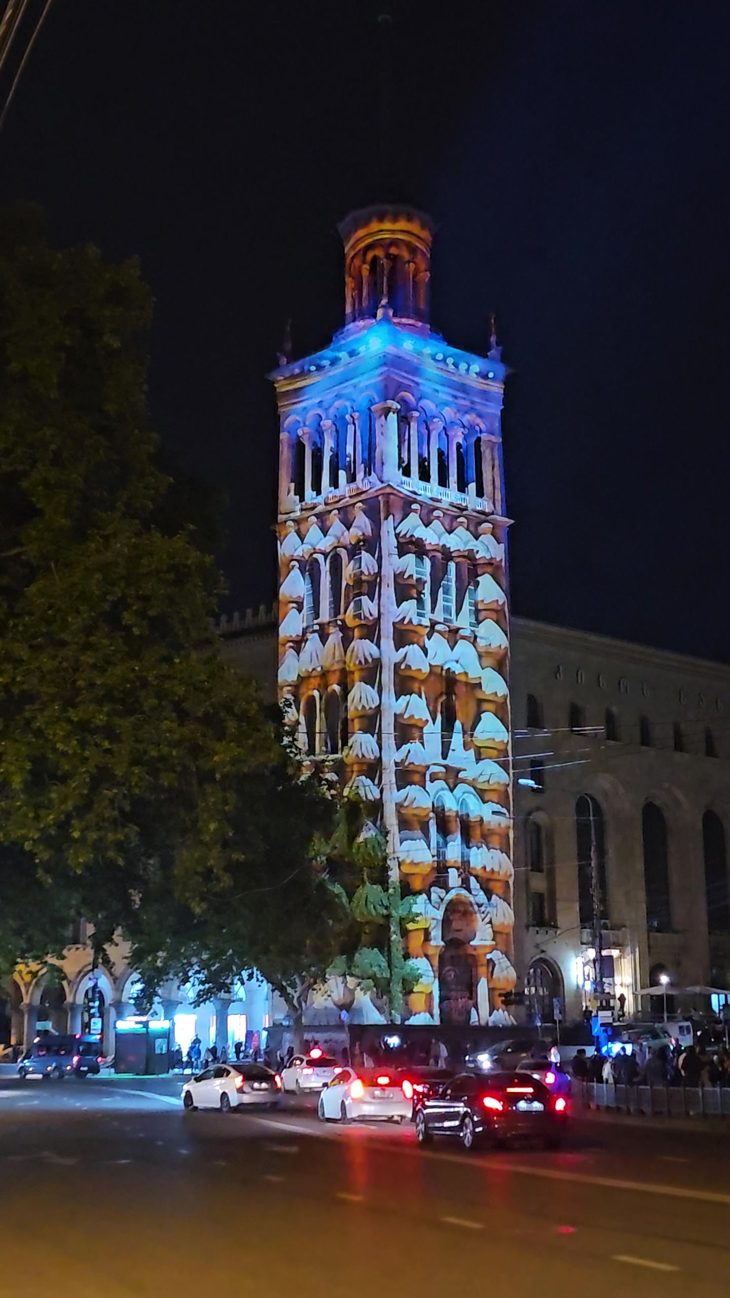 The tower of the Georgian National Academy of Sciences on Rustaveli Avenue in Tbilisi covered in a colourful projection mapping at night